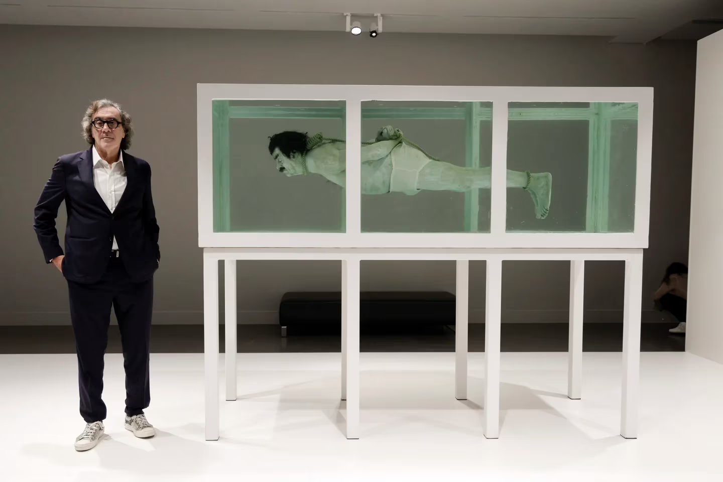 Tatxo Benet er ivrig kunstsamler, helst av verk som er fordømt og forbudt. Her ved verket «Shark» av David Cerny, som viser en hengt, horisontal Saddam Hussein i en glasstank. Verket og tittelen refererer til «The Physical Impossibility of Death in the Mind of Someone Living» av Damien Hirst. (Foto: Infobae.)