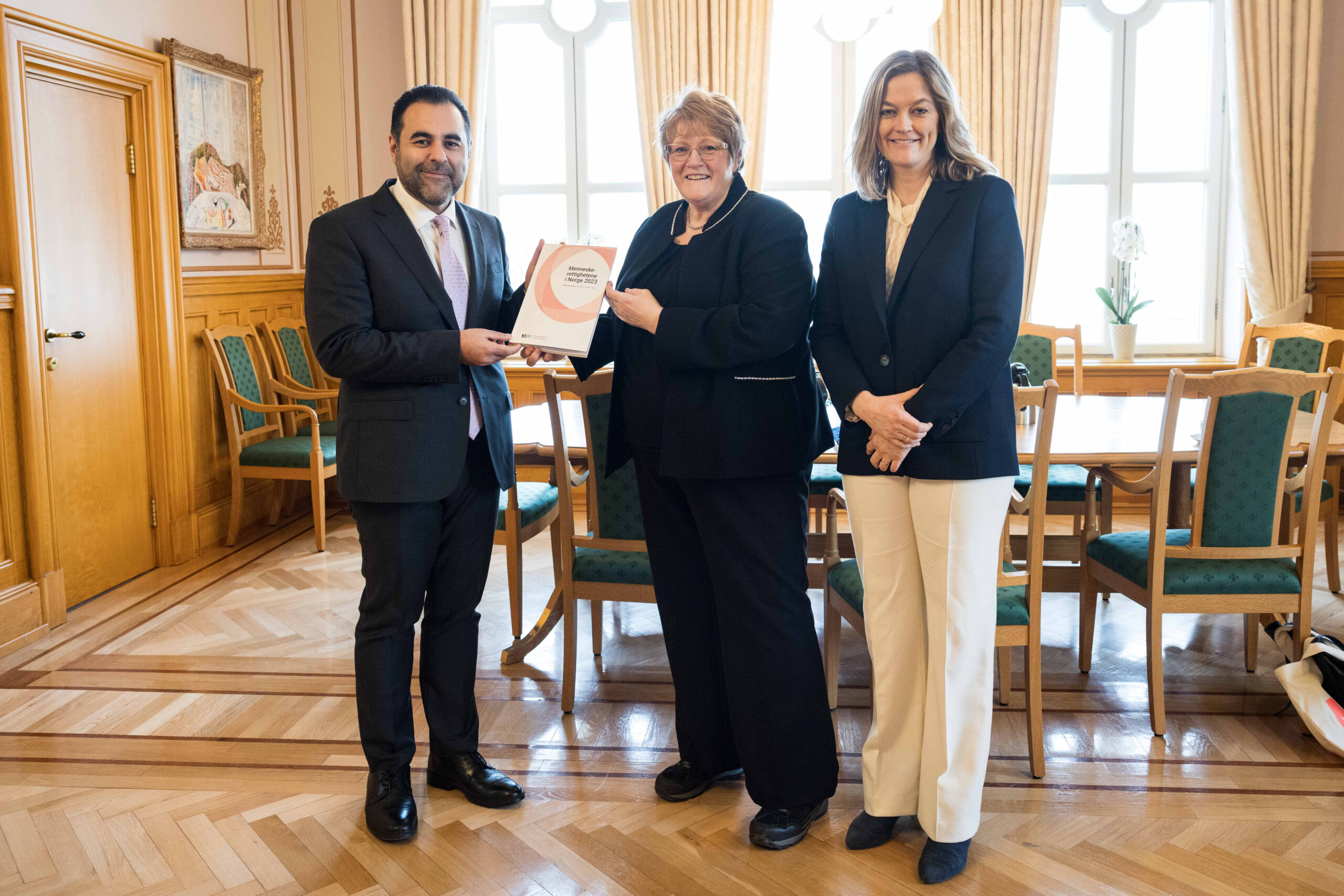 Stortingspresident Masud Gharahkhani mottar NIMs årsmelding for 2023 fra styreleder Trine Skei Grande og direktør Adele Matheson Mestad. (Foto: Peter Mydske/Stortinget.)