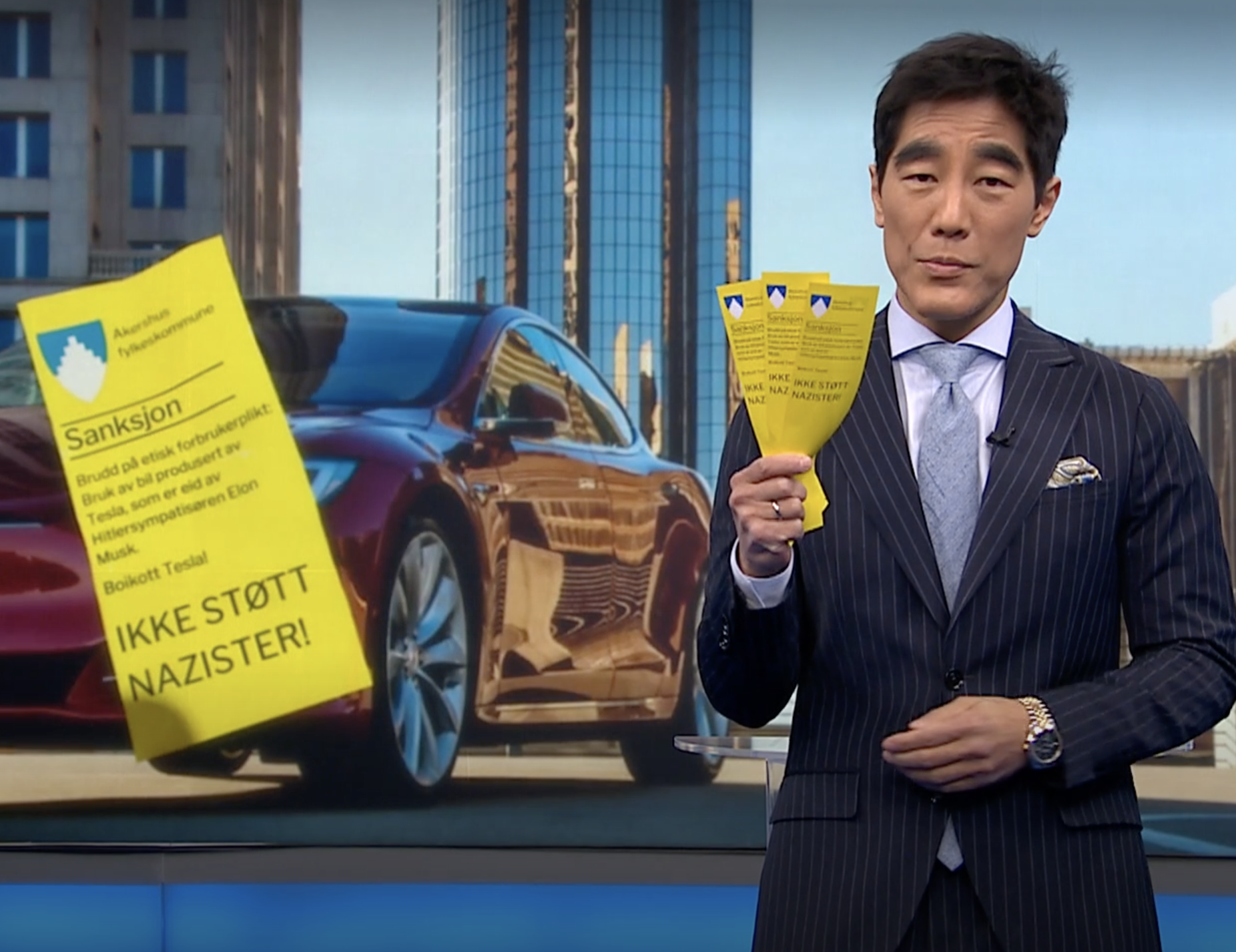 Fredrik Solvang med en bunke falske parkeringsbøter laget av Rød ungdom. (Skjermbilde: Debatten/NRK.)